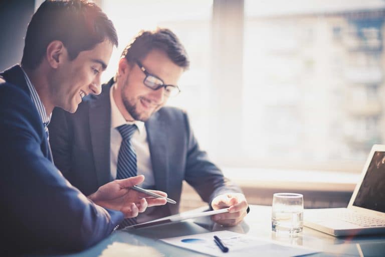 Two men in business suits collaborating on a tablet.